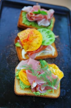 Open-faced sandwiches with heirloom tomatoes, prosciutto, figs, avocado, dill and basil