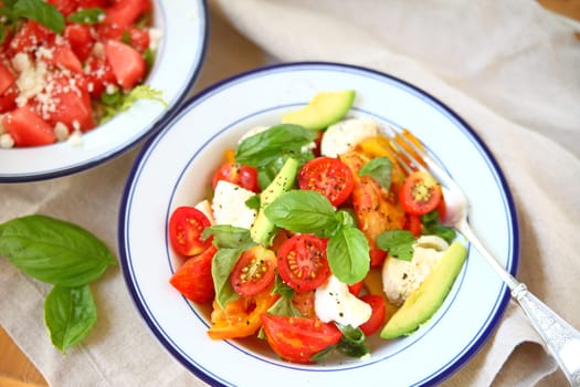 Overhead view of fresh caprese with watermelon salad alongside