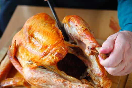 A man carves the leg from a turkey on a cutting board.
