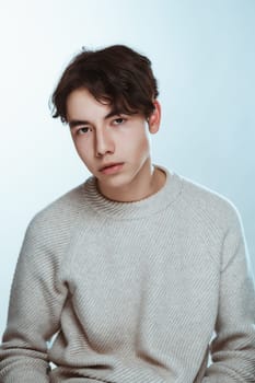 Studio portrait young man in grey sweater on white background.
