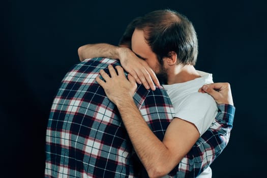 two guys hugging on a dark background.