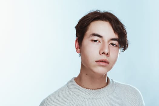 Studio portrait young man in grey sweater on white background.