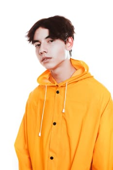portrait of a teen guy in a yellow raincoat brunette in the studio.