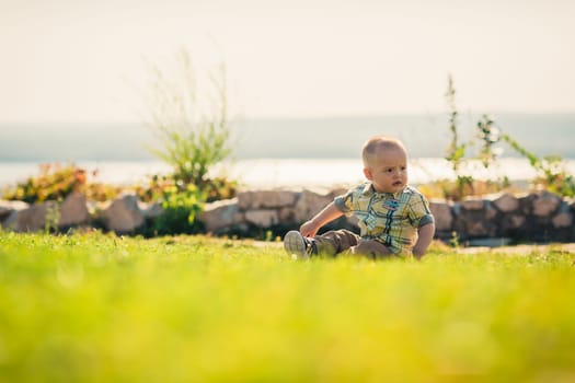 Baby boy on green grass nature background.