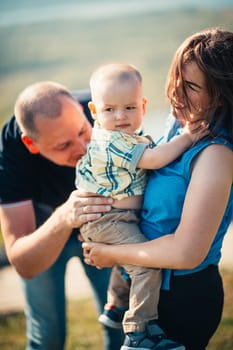 Happy family with baby son on nature background.