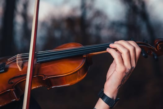 young man playing violin in the autumn forest.