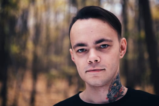 portrait of a man with tattoo in the autumn forest.
