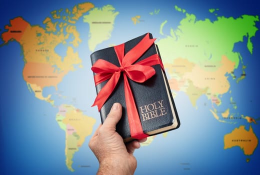 Hand giving the Holy Bible gift against world map.