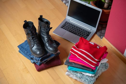 pile of second hand clothing and  shoes with computer on floor in living room