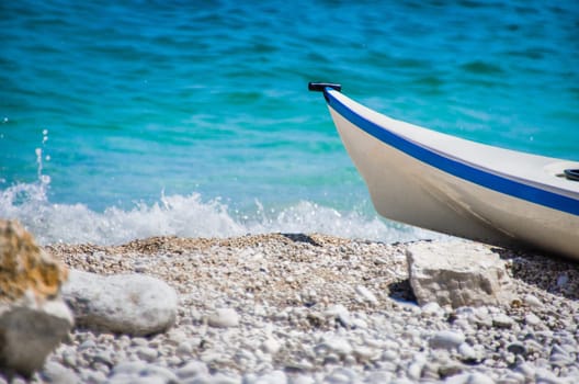 bow small boat sea waves crashing shore pebble beach .