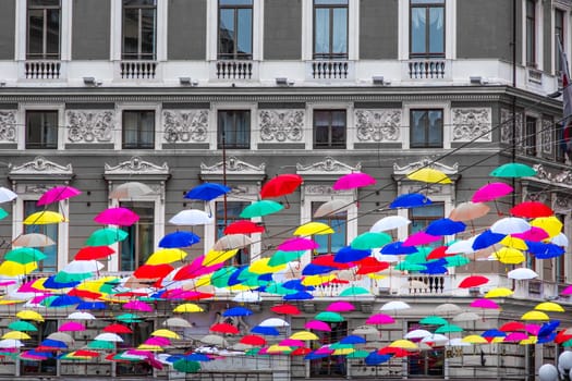 coloful suspended umbrellas hanging n black and white building background