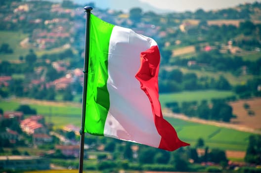 a waving italian flag wave countryside in background .