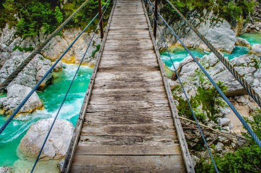 wooden pedestrian bridge footbridge over river Soca in Slovenia hanging in wild background personal perspective point of view pov .