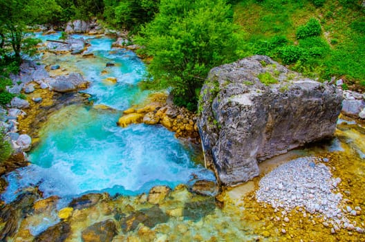 the emerald green waters fall river side bed of Soca river or Isonzo river between Triglav National Park in Slovenia and Caporetto in Italy .