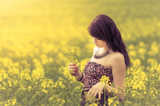 Attractive young beauty girl enjoying the warm sunny sun in nature rapeseed field takes time feeling sustainability and contemplation.