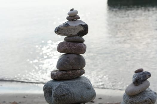Stones stacked on top of each other on the beach with sea view in the background
