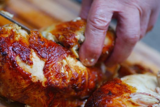 A man cuts up a rotisserie chicken