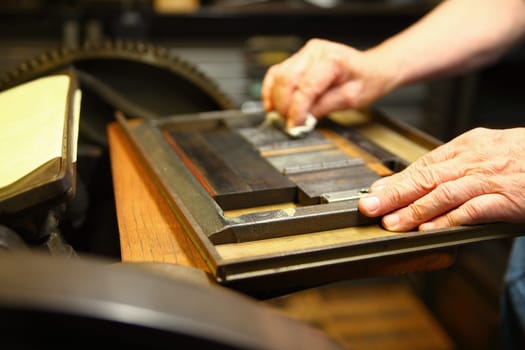 Man wipes clean a block of type in a printing chase