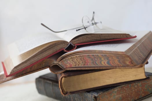 Old books stacked with reading glasses on top and room for text