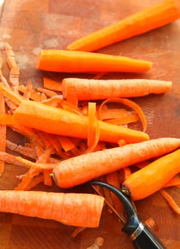Vertical view of raw carrots and peeler with room for text