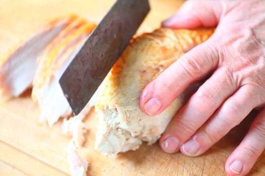 A man slices turkey white meat into slices