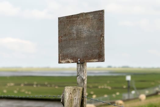 Wooden sign on a post with copy space in front of a North German coastal landscape