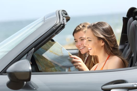Two tourists reading a map searching destination in a convertible car on summer vacation