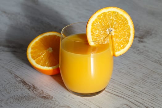 Orange juice in a glass on a wooden background, freshly squeezed