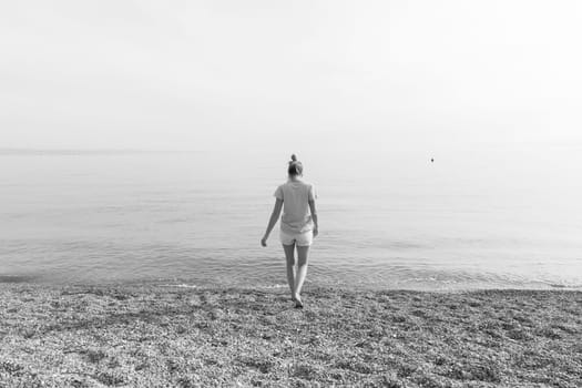 Happy Carefree Woman Enjoying Late Afternoon Walk on White Pabbled Beach in Summer.