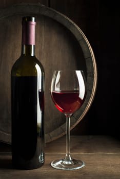 Glass and bottle of red wine on wooden background. Wine background.