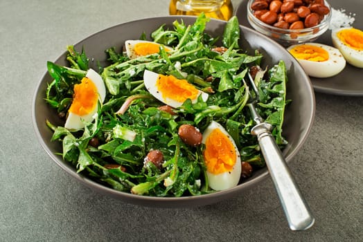 Fresh healthy dandelion salad with eggs and beans close up
