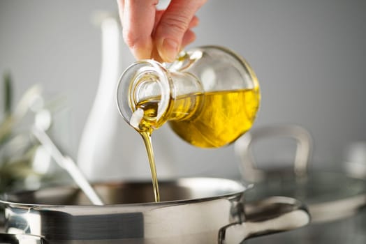 Cooking meal in a pot. Bottle of Extra virgin oil pouring in to pot for cooking meal. Healthy food concept.