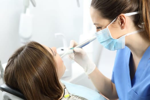 Close up of a dentist working with a patient teeth sitting on a chair in a clinic box with medical equipment in the background