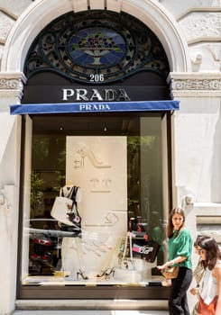 Women walk in front of a Prada store indifferent to the window shop, in Lisbon, Portugal