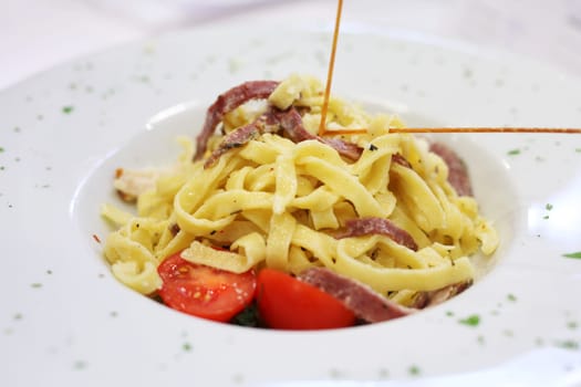 A plate of Fettucine with tomatoes and bacon