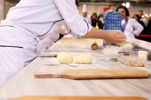 A pizza maker is preparing a pizza from dough