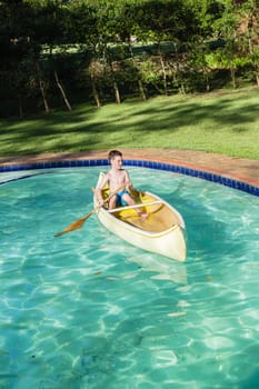 Boy swimming pool water with kayak canoe paddle playing childhood.