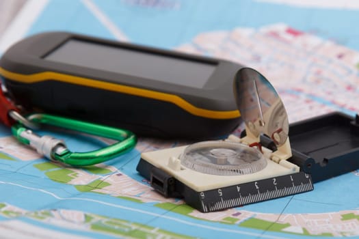 modern handheld GPS device and old tourist compass on map background