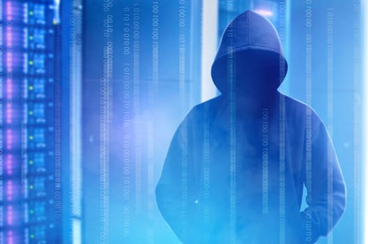 Hacker in black hoodie standing with binary code on virtual screen with modern storage of server in the data center on the background