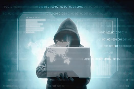 Hacker in black hoodie holding laptop with virtual display server data, chart bar, binary code and world map over dark background