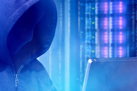 Close up view of hacker in black hoodie holding laptop with binary code on virtual screen with modern storage of server in the data center on the background