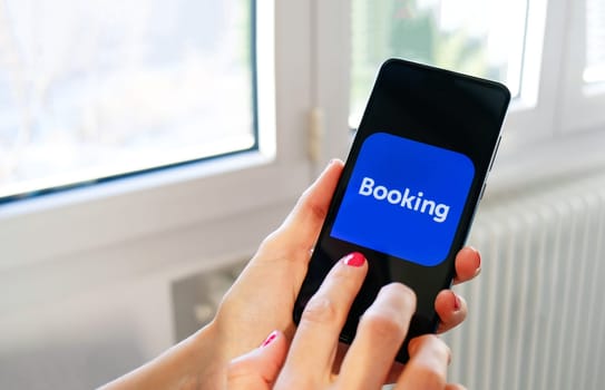 hand use Booking travel app icon on smartphone in Bologna, Italy, 08 March 2019