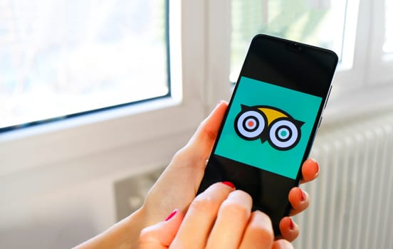 hand use Tripadvisor travel app icon on smartphone in Bologna, Italy, 08 March 2019