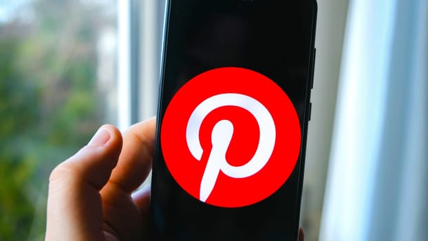 hand use Pinterest app symbol on smartphone in Bologna, Italy, 08 March 2019