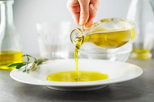 Bottle of healthy virgin olive oil pouring to plate close up