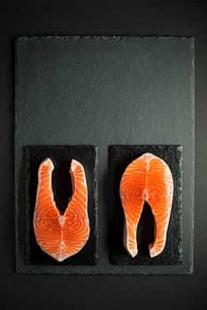 Fresh salmon fish on black background. Prepare for cooking healthy meal.