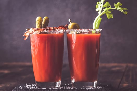 Two glasses of Bloody Mary garnished with gherkins and celery stalk