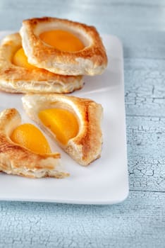 Puff pastry with canned peaches on the wooden table