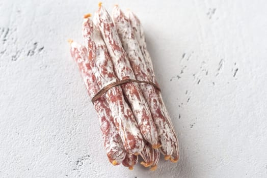 Snack fuet sausages on the wooden background: top view
