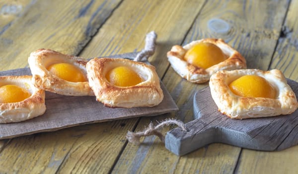 Puff pastry with canned peaches on the wooden table